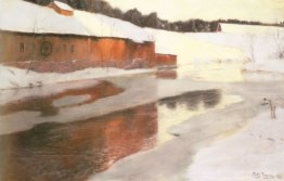 Un bâtiment d'usine près d'une rivière glacée en hiver