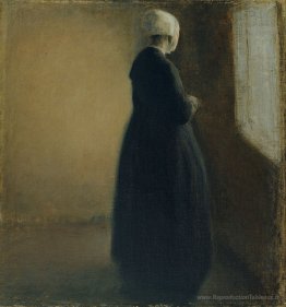 Une vieille femme debout près d'une fenêtre